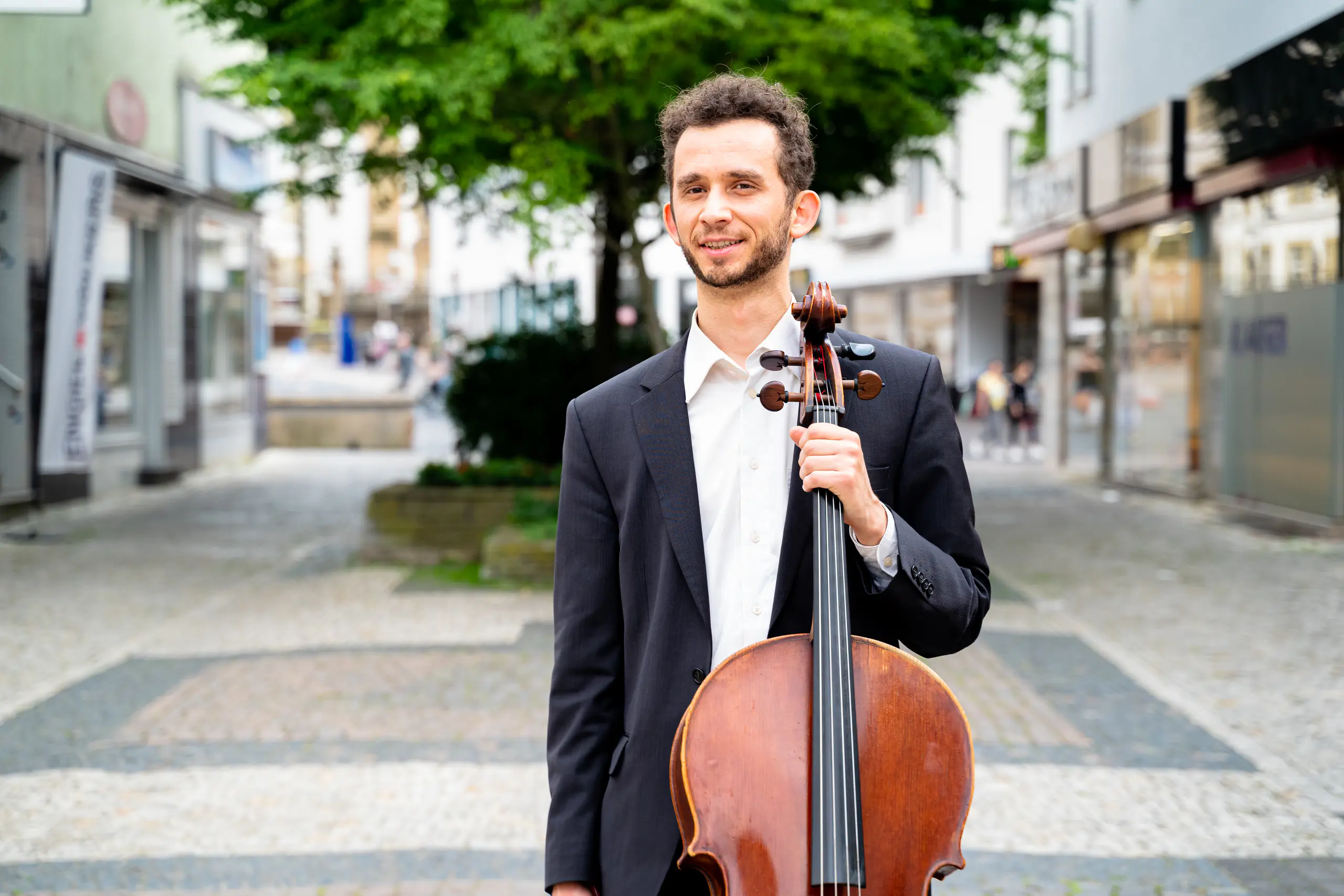 Ventsislav Harkov standing with his cello in a pedestrian street