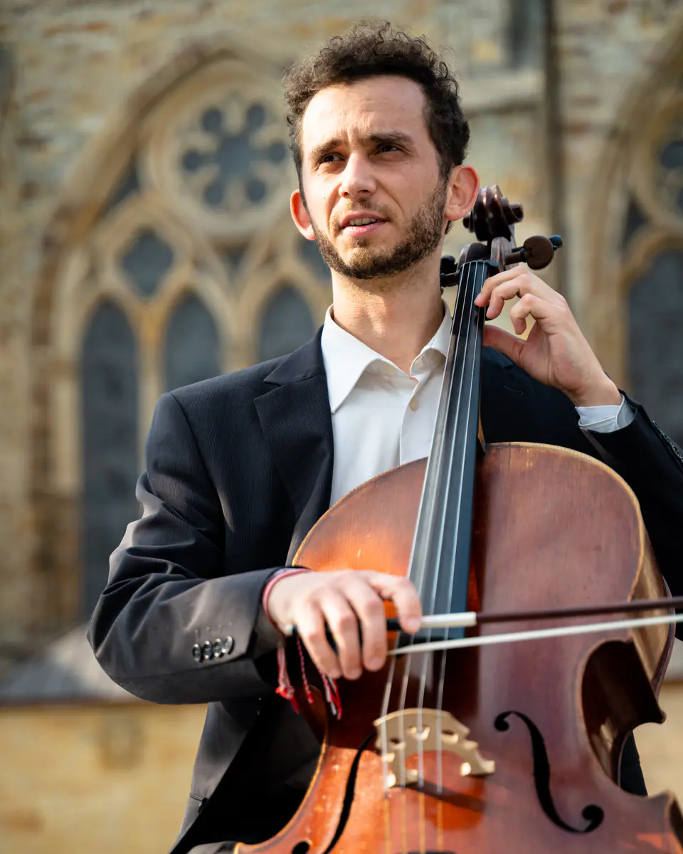 Ventsislav Harkov playing the cello in front of a Gothic church window